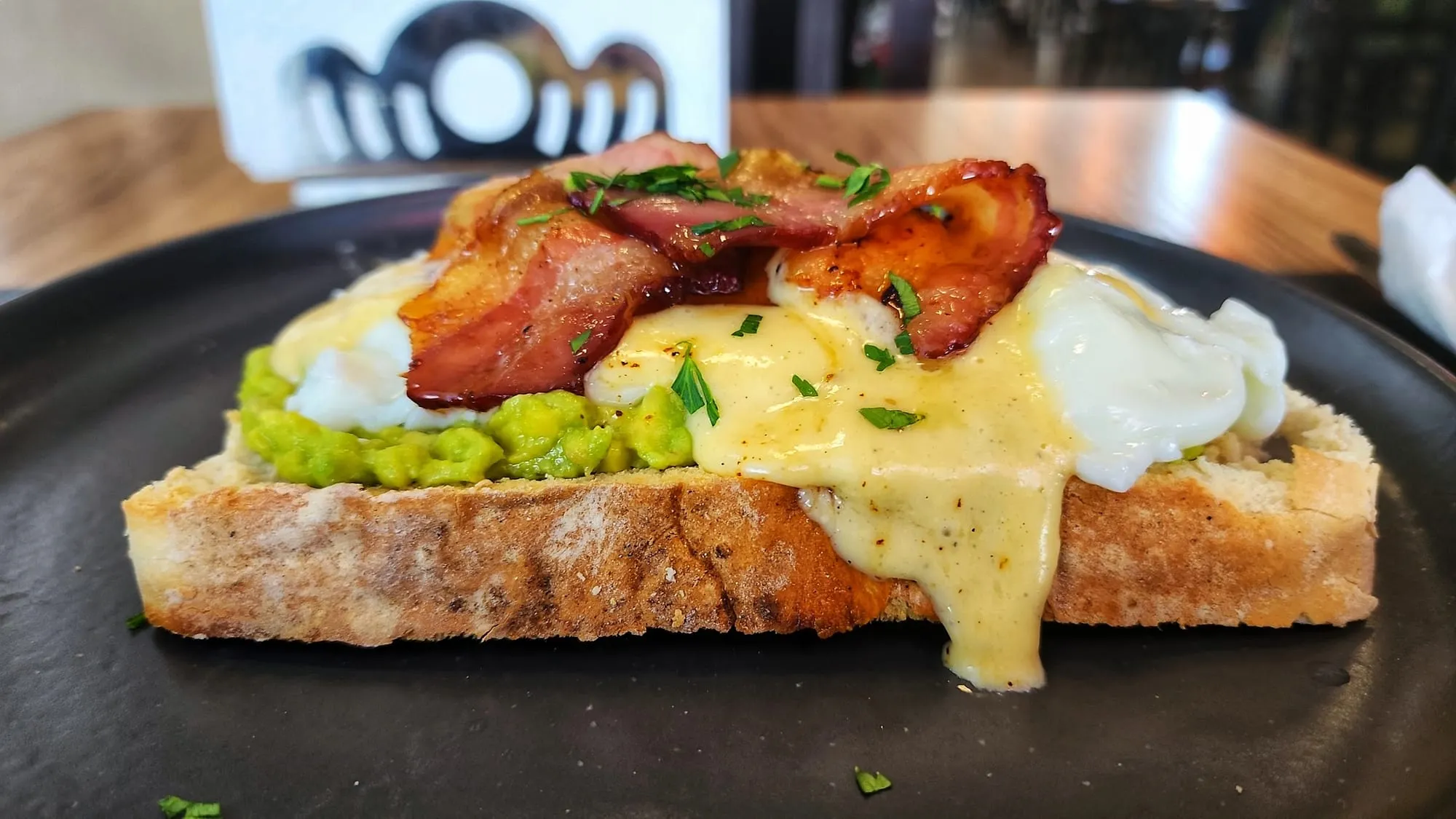 Ovos benedict com bacon, abacate e molho holandês sobre pão