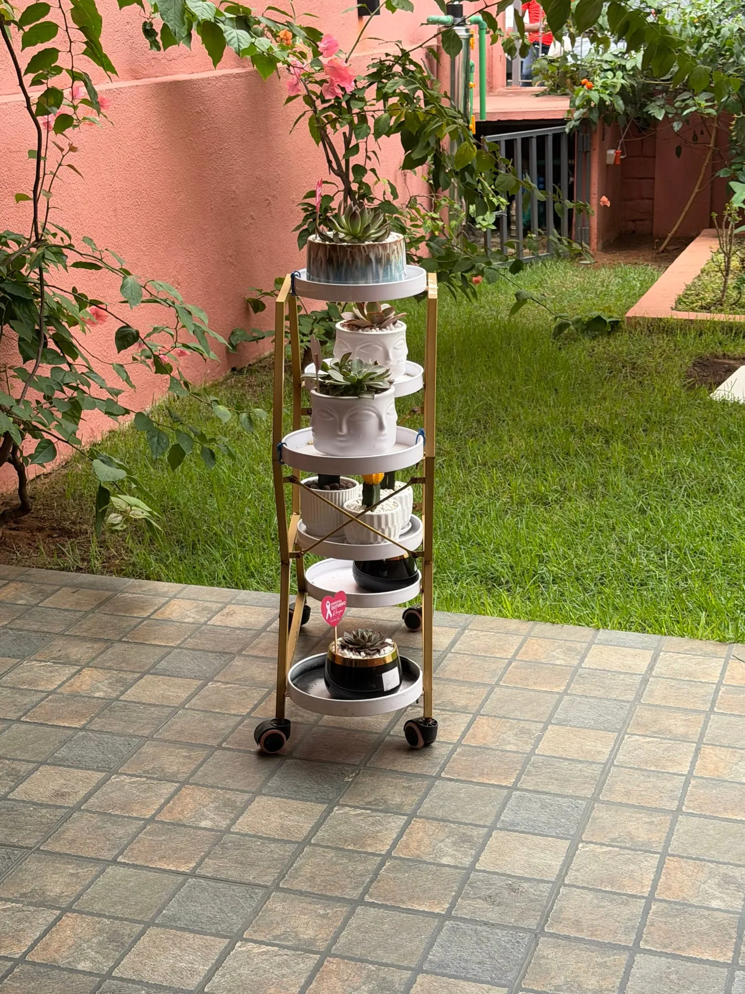 Pátio com chão de azulejo, um carrinho com plantas e o jardim
