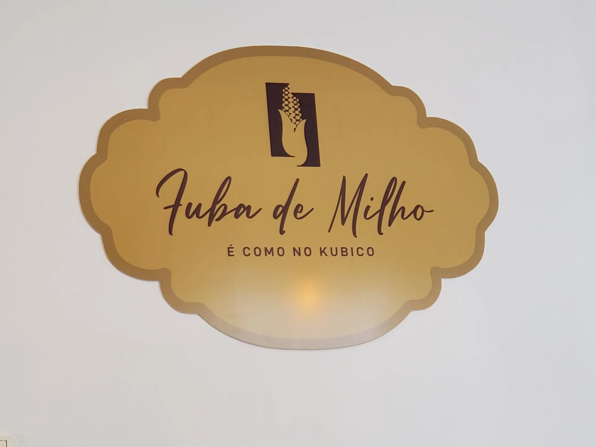 Placa dourada na parede com o logótipo e a frase É como no kubico