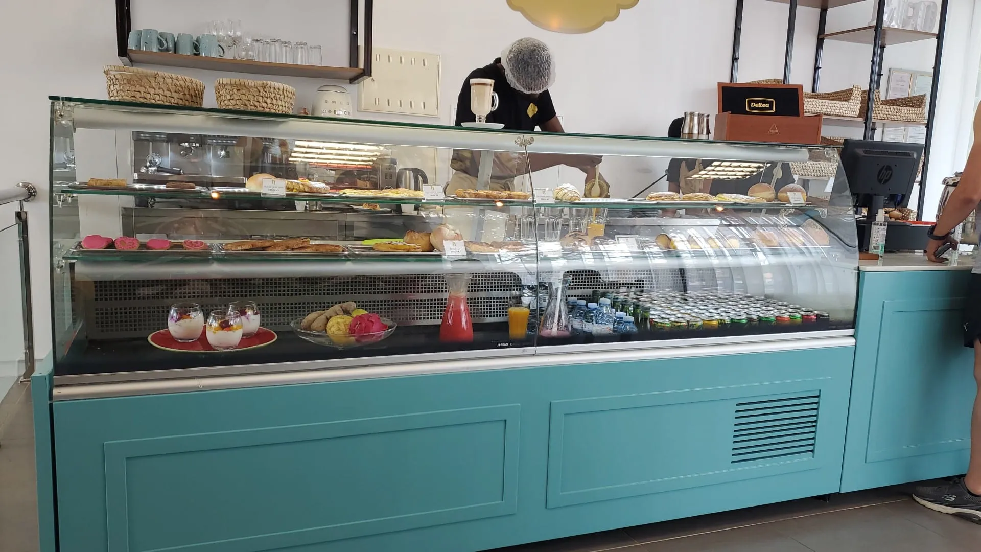 A vitrine turquesa da pastelaria, com bolos, sobremesas e sumos